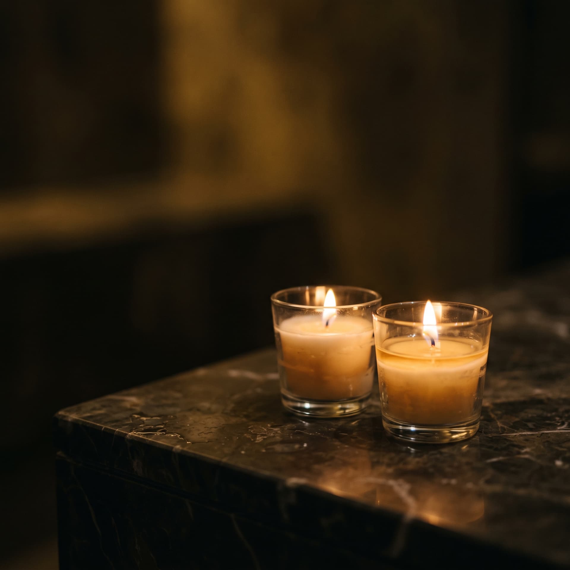 Dos velas encendidas sobre una esquina de mármol oscuro