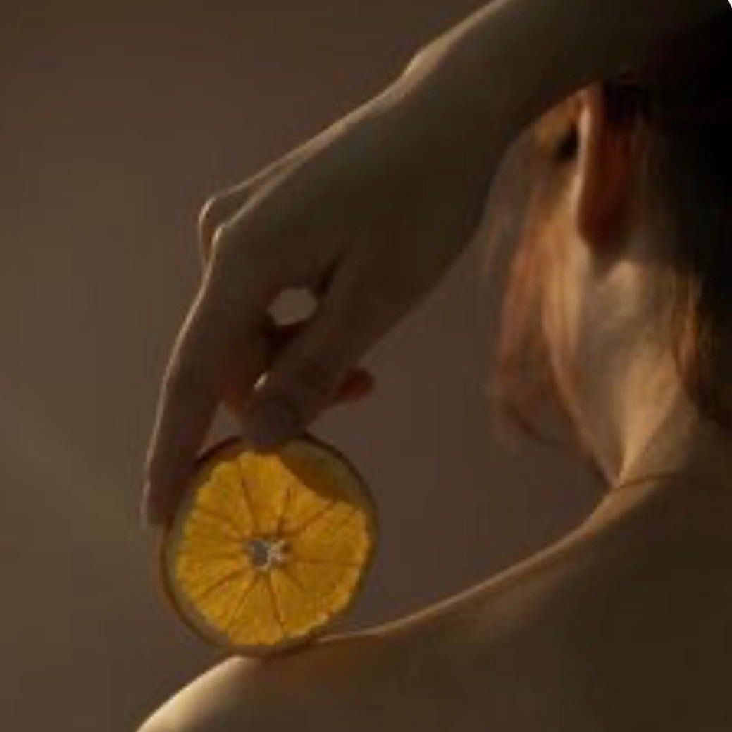 Mano sosteniendo una rodaja de naranja con luz cálida